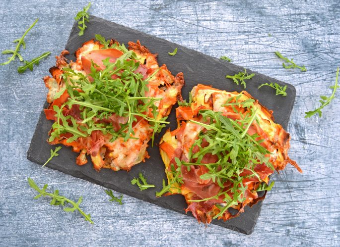 Opskrift rodfrugt rösti anrettet på en skiferplade toppet med rucola