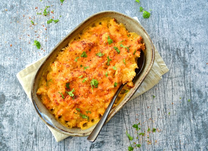 Opskrift mac and cheese gratineret med rasp i et ildfast fad med en sort ske