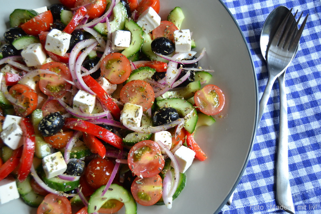 Opskrift græsk salat i en skål på en blå og hvid dug