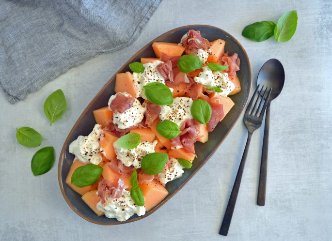 Opskrift på salat med cantaloupe, skinke og burrata, pyntet med frisk basilikum